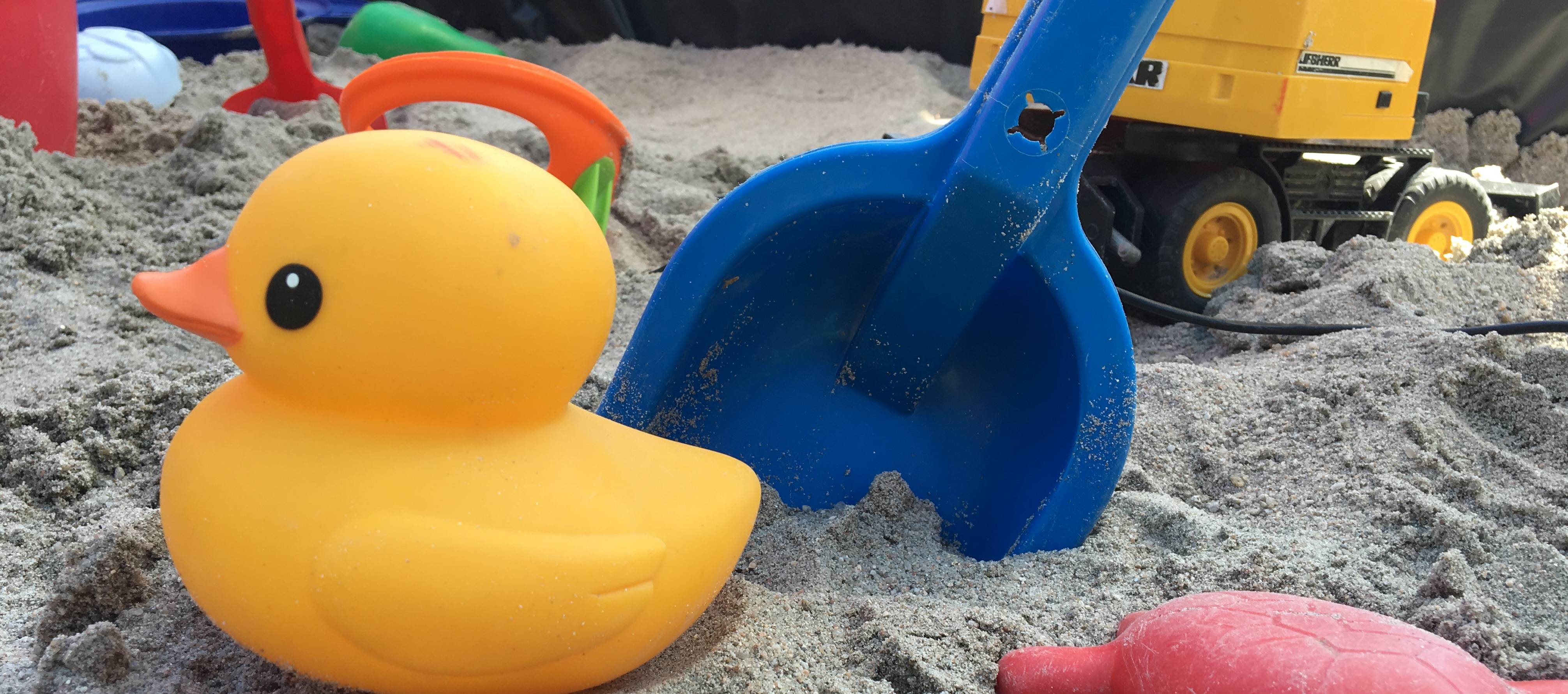  Kind spielt in Sandkasten 